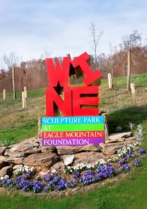 Bright colored sculpture surrounded by flowers in a scuplture trail