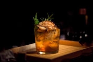 Alcoholic cocktail on wooden table with garnish. 