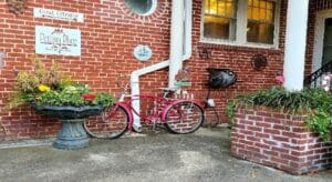 Red bike by brick wall near fountain filled with flowers