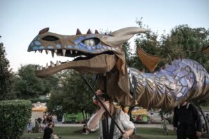 Giant dragon puppet at ren faire with woman master.