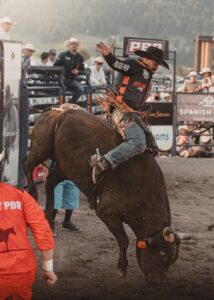 Man bullriding in rodeo arena.