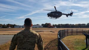 Helecopter mid flight in front of military man. 