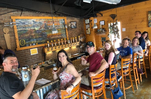 Group of smiling people toasting with beer glasses ar a rustic bar.
