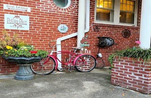 Red bike chained to column near garden planters.