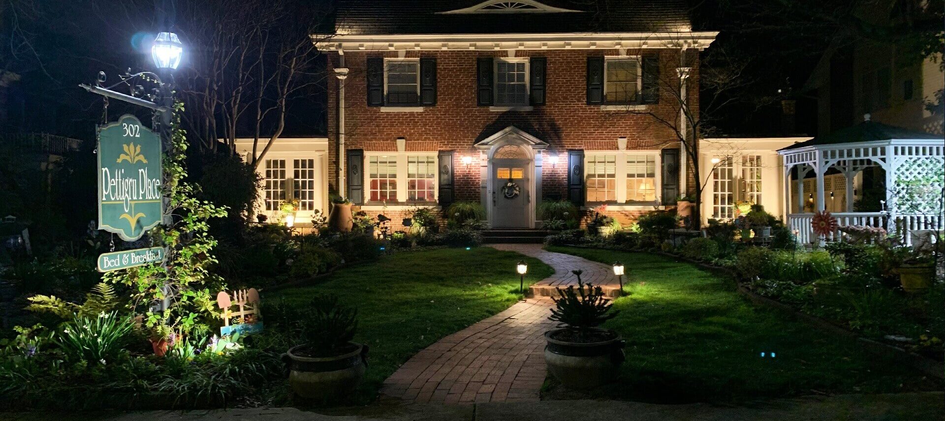 Front of brick faced two story bed and breakfast lit up at night.