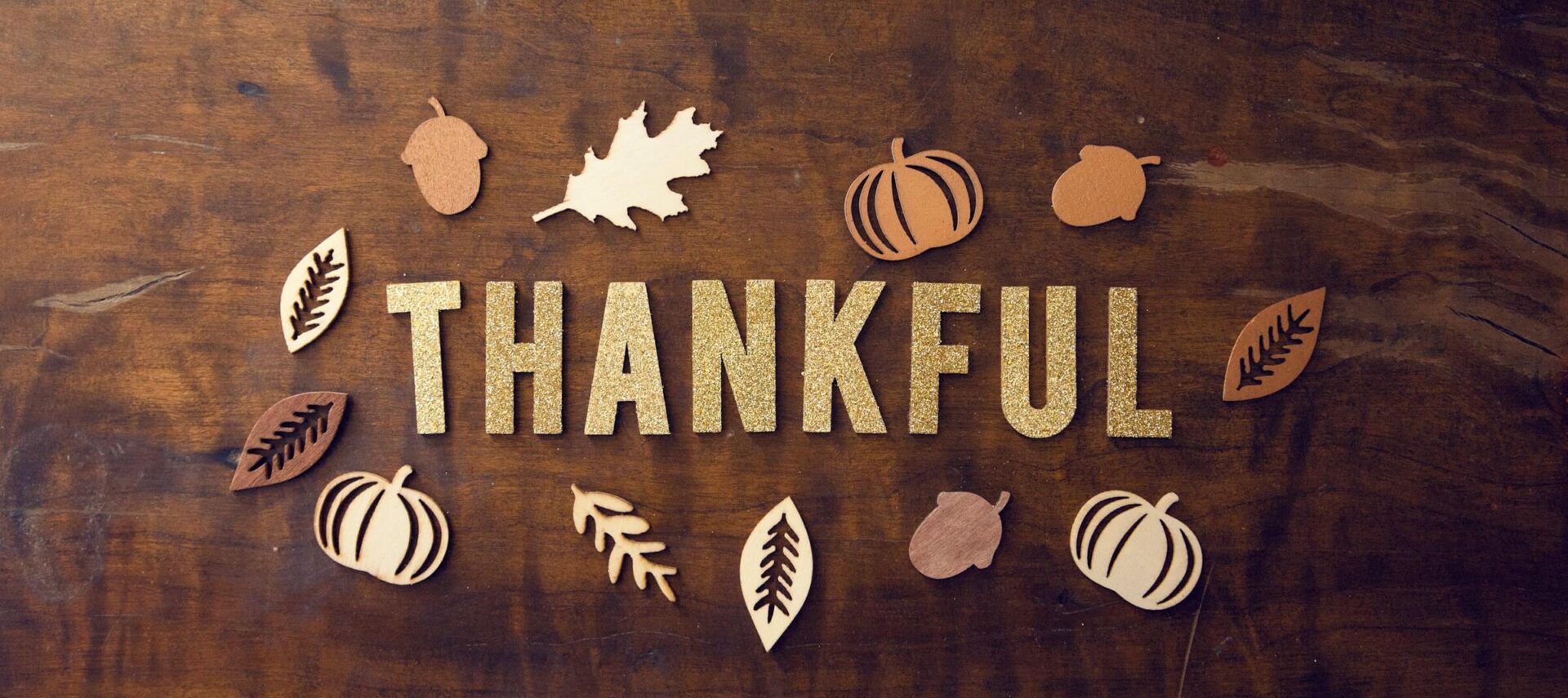 The word Thankful surrounded by leaves on wooden board