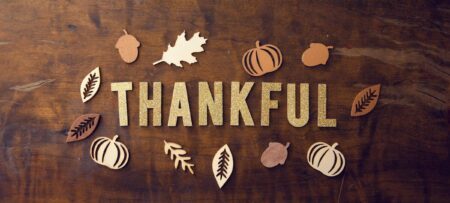 The word Thankful surrounded by leaves on wooden board