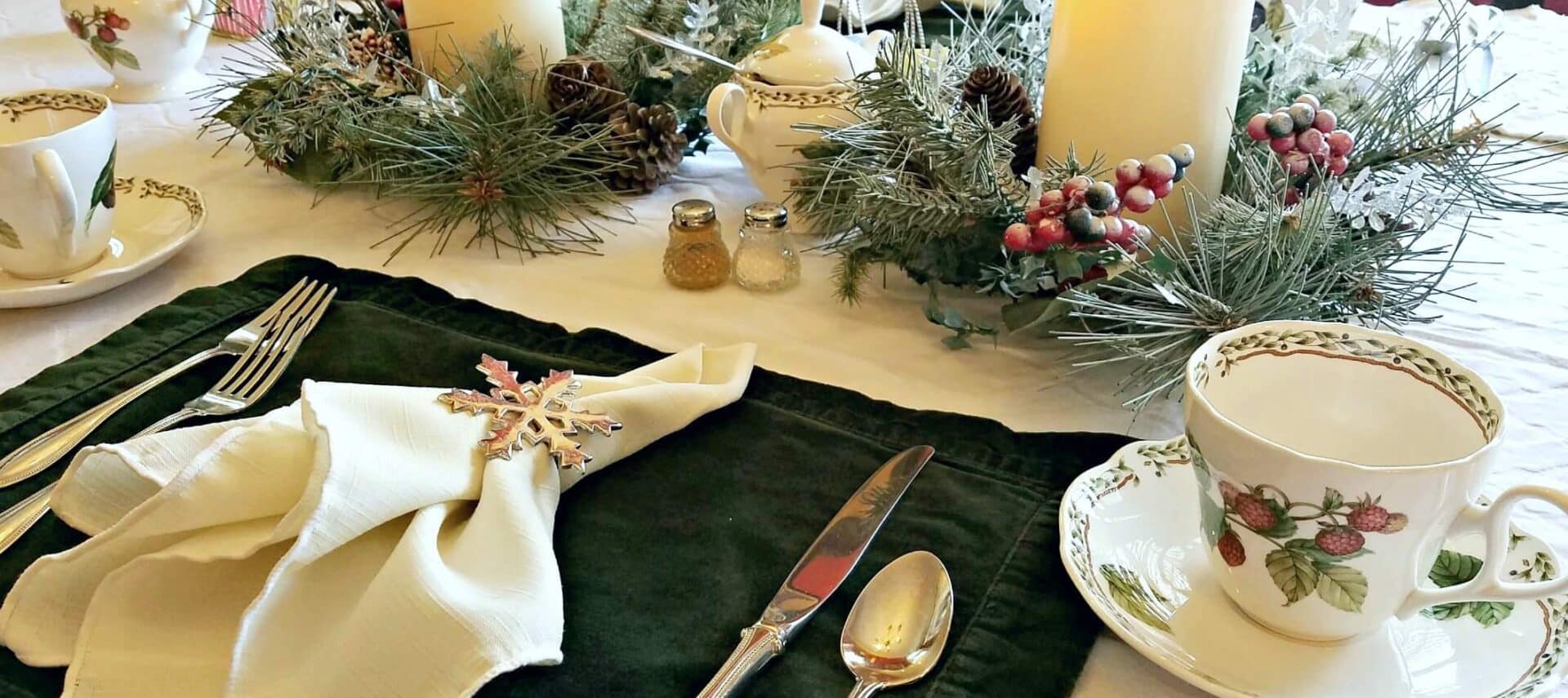 Table setting with white and green linen, candles, and fine china.