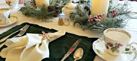 Table setting with white and green linen, candles, and fine china.